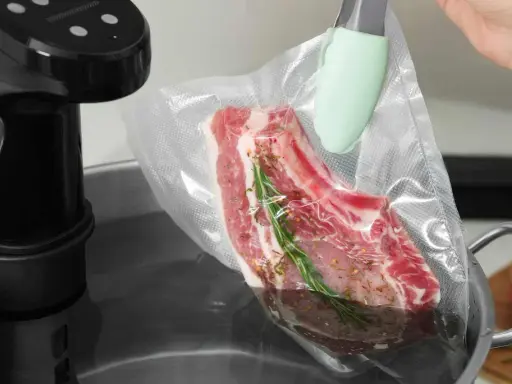 Ein Steak mit Rosmarin und Gewürzen wird für das Suvid Garen in einen Vakuumbeutel gelegt.