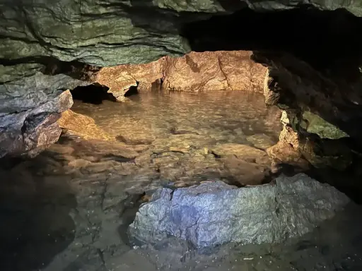 Wnętrze jaskini Radochowskiej z krystalicznie czystą wodą odbijającą skalne ściany.