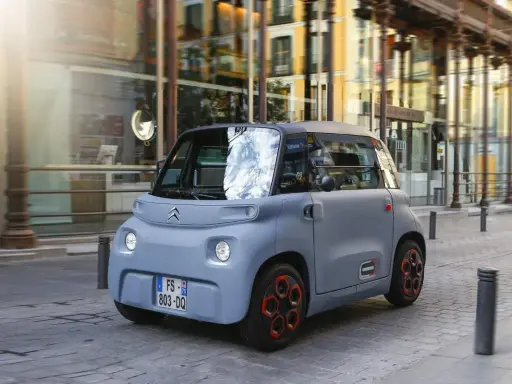 Citroën Ami gris en movimiento por la ciudad. Descubre el carnet AM precio y disfruta de la movilidad urbana.