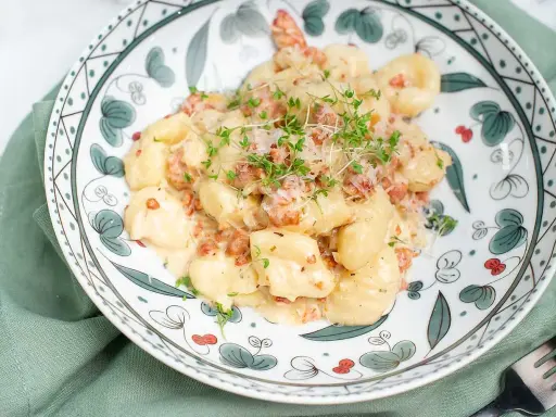 Krämiga gnocchi med salsiccia, toppade med riven ost och färska örter. En härlig rätt som passar perfekt för en mysig middag.