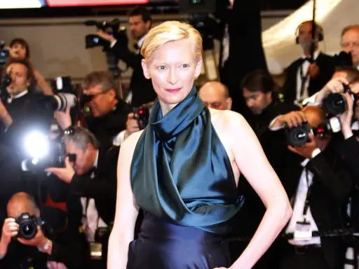 Tilda Swinton poses on the red carpet, surrounded by flashing cameras and eager photographers.