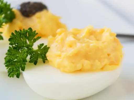 Zwei appetitliche russische Eier traditionell, gefüllt mit einer cremigen Eigelbmasse und garniert mit Petersilie.