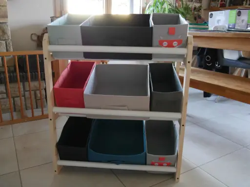 Étagère en bois avec des bacs de rangement pour jouets, dont un décoré d'un chat super-héros. Idéal pour fabriquer un rangement jouet organisé.