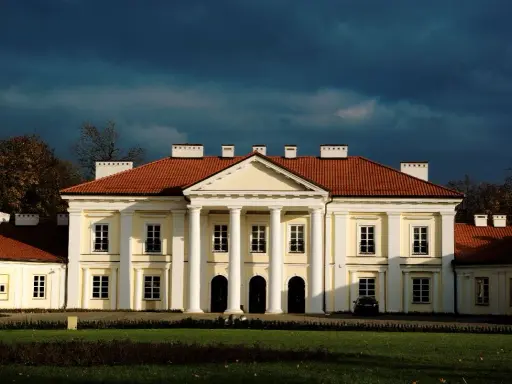 Pałac w Siedlcach, jedna z głównych atrakcji miasta, z charakterystycznym portykiem i czerwonym dachem, na tle burzowego nieba.
