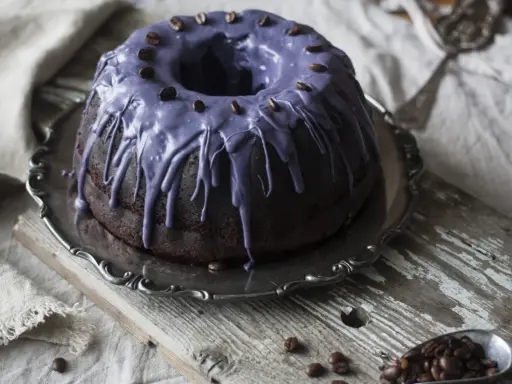 Mörk chokladkaka med lila glasyr och kaffebönor, perfekt för ett chokladkaka recept.
