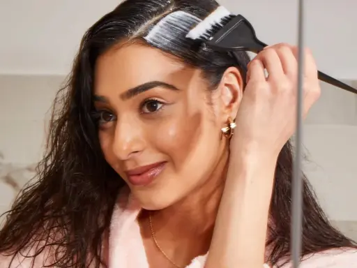 Mujer aplica producto para aclarar pelo castaño oscuro sin decolorar.