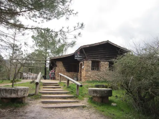 Mesones Riopar: acogedor bar-restaurante de piedra y madera en un entorno natural. Escaleras de acceso y mesas exteriores invitan a disfrutar.