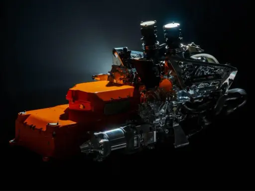 Un vistazo a los futuros motores F1 2026: un complejo sistema híbrido con componentes naranjas y metálicos, listo para la velocidad.