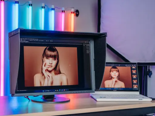 Dwa monitory pokazują portret kobiety. Większy monitor EIZO wyświetla obraz w rozdzielczości 2k, a obok laptop ConceptD.