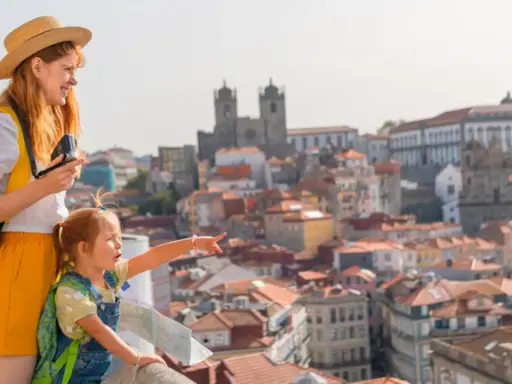 Una madre y su hija disfrutan de las vistas de Oporto con niños, señalando la ciudad histórica.