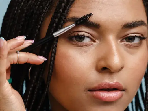 Une femme utilise une brosse pour coiffer son sourcil. La repousse d'un sourcil est une question de patience.