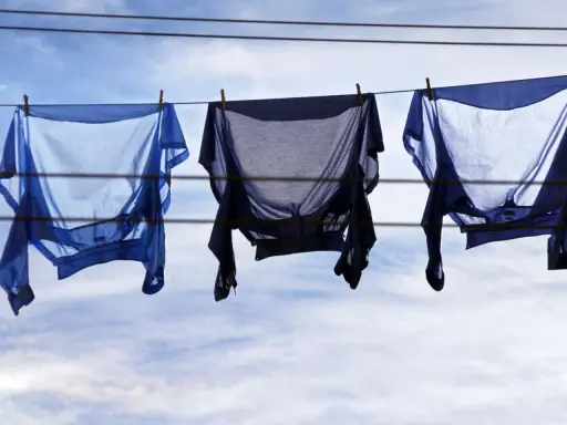 Drei blaue Hemden trocknen auf der Wäscheleine. Sie wurden auf links gewaschen, um die Farben zu schonen.