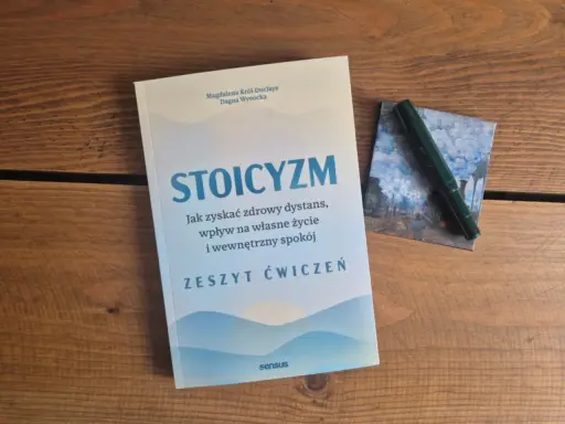 Zeszyt ćwiczeń "Stoicyzm. Jak zyskać zdrowy dystans, wpływ na własne życie i wewnętrzny spokój" obok zielonego pióra. Sztuka życia według stoików.