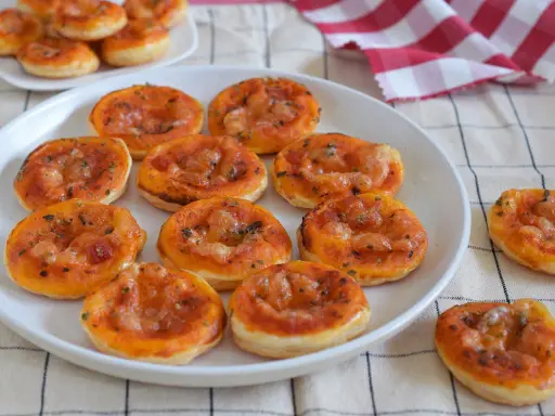 Deliciosas galletas de hojaldre con salsa de tomate y queso, perfectas para un aperitivo.