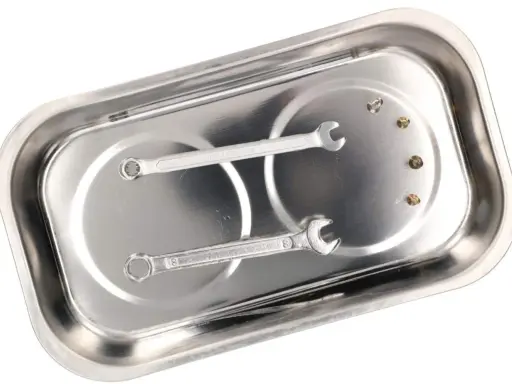 Bandeja magnética de metal con dos llaves inglesas y tres tornillos sujetos.