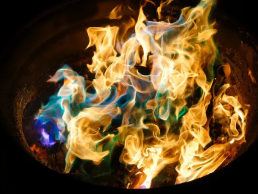 Fiamme danzanti in un braciere, con sfumature blu e verdi che si mescolano all'oro. Un'arte nel fotografare il fuoco.