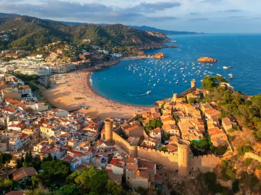 Widok na średniowieczne miasteczko z zamkiem i zatokę pełną łodzi. To idealne miejsce na odkrywanie atrakcji Costa Brava.