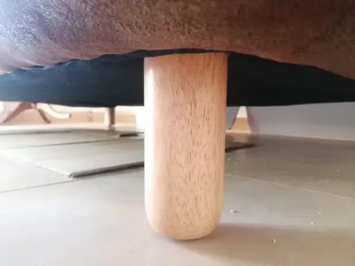 Una pata de madera de un canapé, mostrando cómo levantar un canapé del suelo para limpiarlo o moverlo.