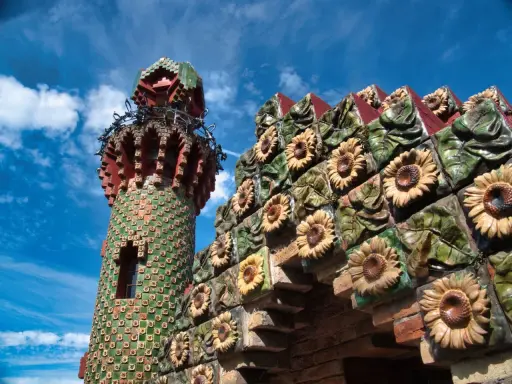 Bunte Sonnenblumen zieren die Fassade eines Turms in Comillas, Spanien.