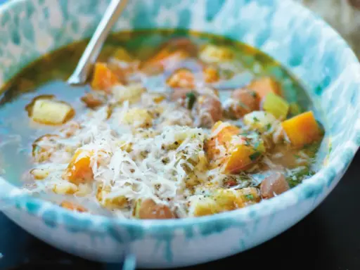 En närbild av en skål med mustig rotfruktssoppa, toppad med riven ost. Ett perfekt soppa recept för kalla dagar.