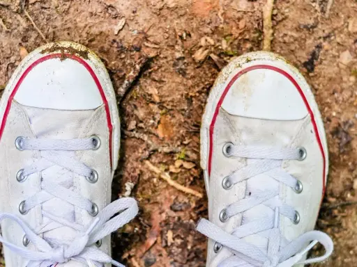 Brudne białe trampki na ziemi. Czas dowiedzieć się, jak wyczyścić białe podeszwy, by znów lśniły!