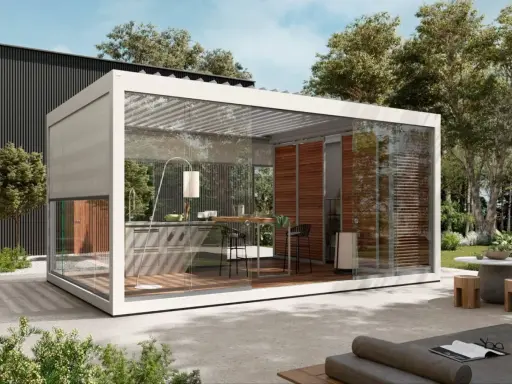 Moderna cucina esterna con tettoia in vetro, completa di bancone, sgabelli e un'elegante lampada da terra.