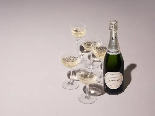 Flasche Laurent-Perrier Champagner neben gefüllten Gläsern. Ein süßer Champagner für besondere Anlässe.