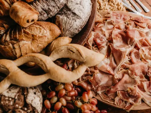 Un assortiment de pains artisanaux, de jambon cru et de raisins, parfait pour un pain sandwich italien gourmand.