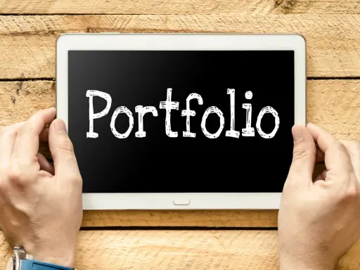 Ręce trzymają tablet z napisem "Portfolio". Idealny do prezentacji prac podczas studiów.