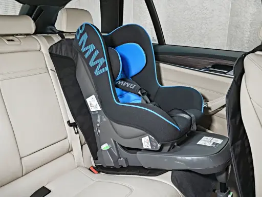 Fotelik dziecięcy BMW z systemem pasy isofix zamontowany na jasnej, skórzanej kanapie samochodowej.