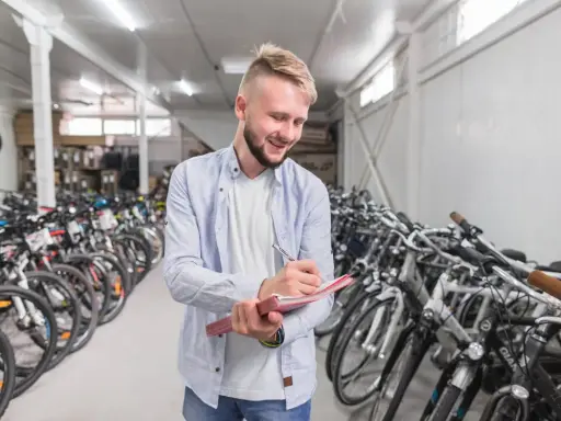 Uśmiechnięty sprzedawca notuje w zeszycie, otoczony rzędami rowerów amerykańskich marek.