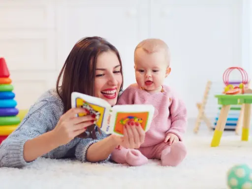 Mama czyta książeczkę kolorową, a jej 2 letnie dziecko z zaciekawieniem słucha.