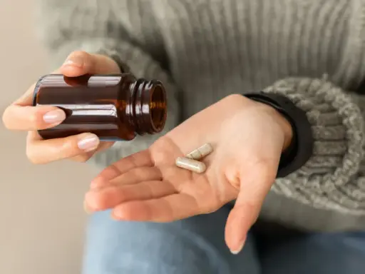 Dłoń z kapsułkami, które mogą wywołać biotyna skutki uboczne.
