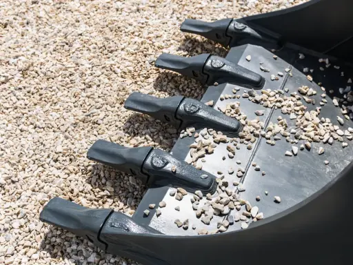 Dientes de excavadora sobre grava, una forma de como compactar tierra sin rodillo.