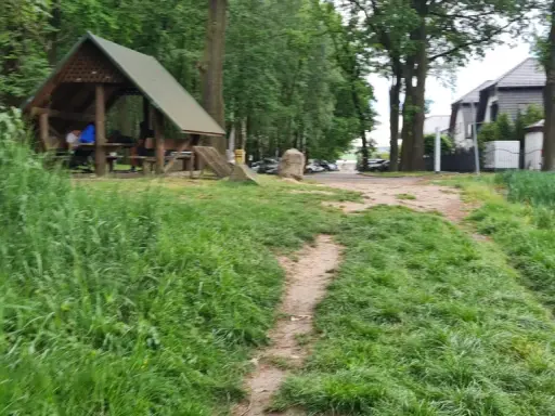 Ścieżka wśród zieleni prowadzi do altany, idealnej na odpoczynek po przejażdżce po trasach rowerowych Ruda Śląska.