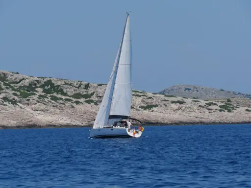 Segelboot gleitet durch das tiefblaue Wasser der kroatischen Kvarner Bucht, vorbei an felsigen, grünen Inseln.