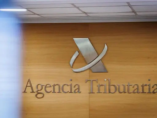 Logo y nombre de la Agencia Tributaria en una pared de madera.