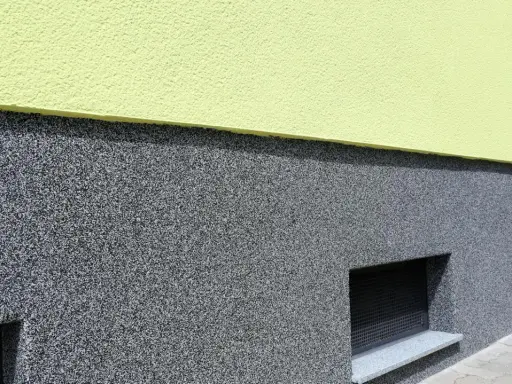 Der Sockel ist mit einem robusten, grauen Körnchenputz verputzt, der gut zu den kleinen Kellerfenstern passt.