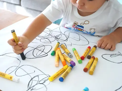 Bambino disegna con pastelli su foglio bianco. I disegni dei bambini sono un modo per esprimere emozioni, ma quando preoccuparsi?