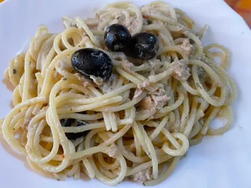 Un piatto di spaghetti conditi con tonno e olive nere, un classico della cucina italiana.