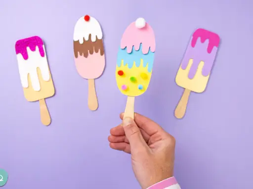 Bunte Eis-Bastelvorlagen: vier selbstgemachte Eis am Stiel aus Papier, dekoriert mit Glitzer und Pompons.