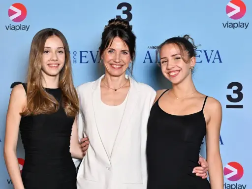Tuva Novotny med sina barn, glada och leende framför en blå bakgrund med ViaPlay-logotypen.