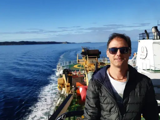 Uomo su nave, con mare e terra all'orizzonte. Un vero oceanografo significato, immerso nella sua ricerca.