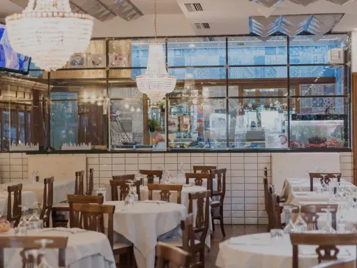 Interno del ristorante Amerigo a Rimini, con tavoli apparecchiati e lampadari eleganti.