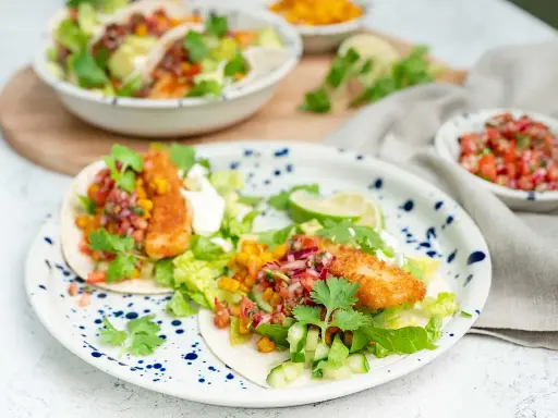 Två läckra fish tacos med krispig fisk, färsk salsa, majs och grönsaker. En festlig måltid!