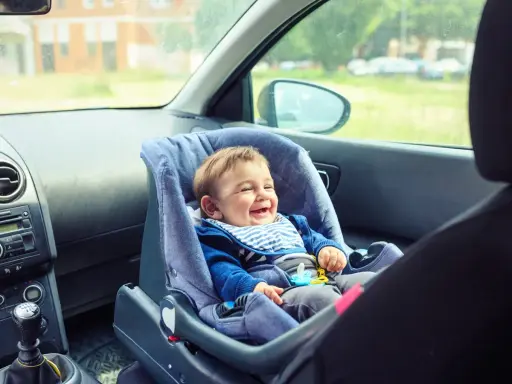 Bebé feliz en silla de coche, asiento delantero, listo para la aventura.