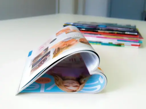 Ein aufgeschlagenes Magazin, das wie ein Herz geformt ist, liegt auf einem Tisch. Im Hintergrund stapeln sich weitere Ausgaben der aero zeitschrift.