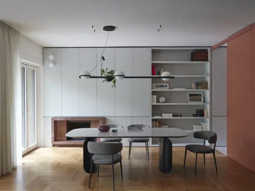 Sala da pranzo moderna con tavolo ovale, sedie imbottite e libreria a giorno. Le pareti grigio luminoso creano un'atmosfera sofisticata.