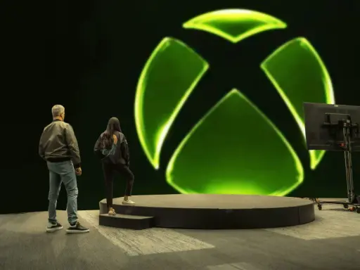 Osoby stoją przed wielkim zielonym logo Xbox. Czy to zapowiedź nowej gry, czy może Xsolla co to za platforma?