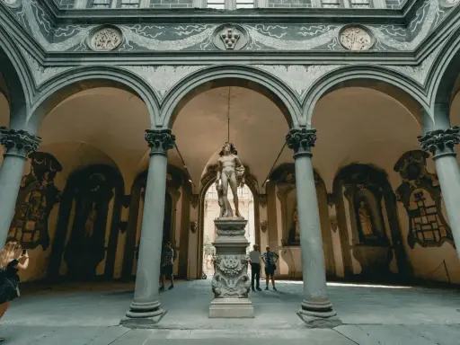 Cour intérieure de Florence avec une statue antique au centre. Une femme prend une photo de la statue florence.